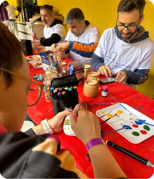 Pessoas pintando vasos em oficina de artesanato do Instituto Amor Philia